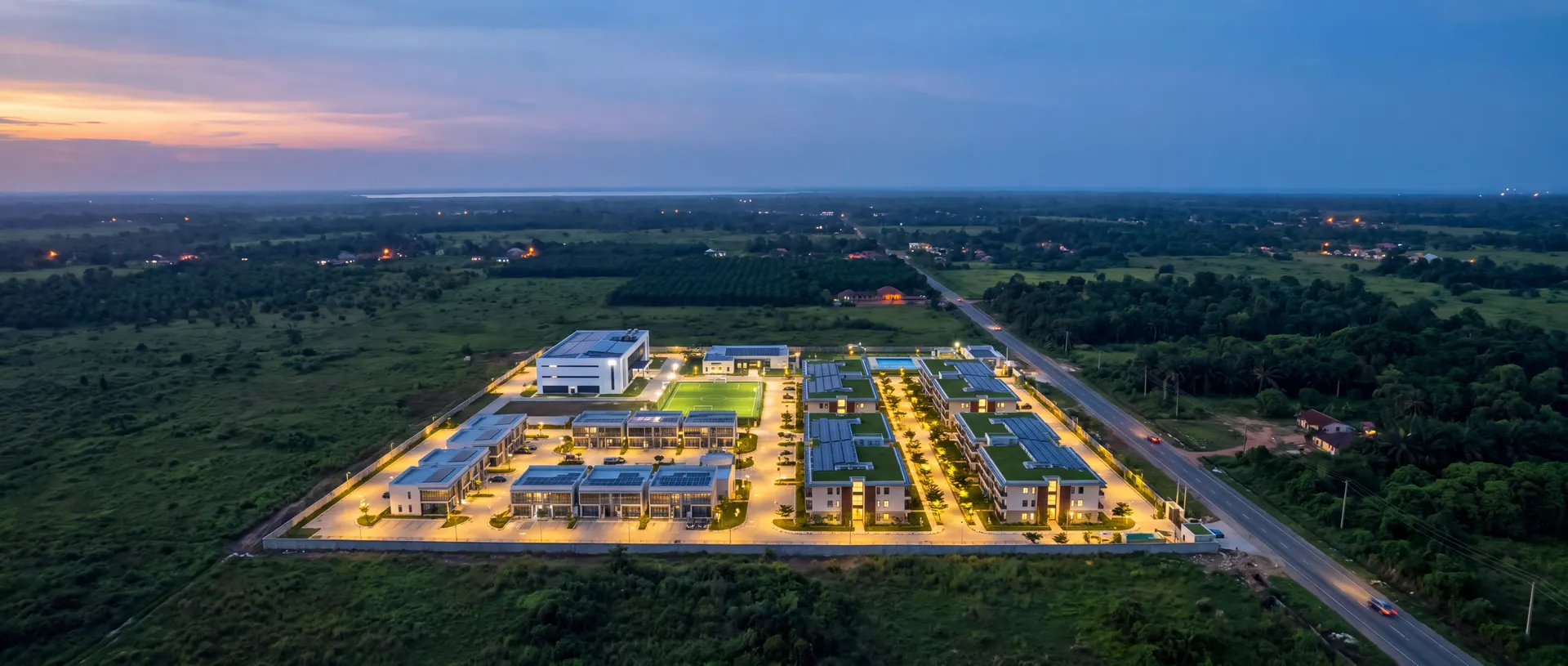 Dusk aerial view of a compact smart industrial estate in flat green countryside